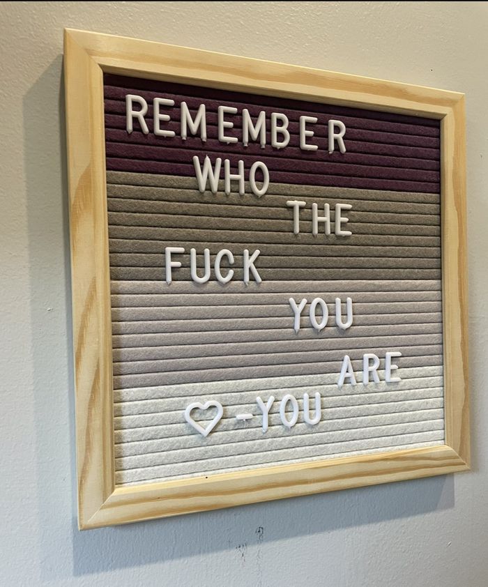 A felt letterboard in a wooden frame spelling out Remember Who The Fuck You Are, heart, You.